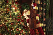 © ZaStock - Santa Clause helps his little girl assistant decorating Christmas tree with toys. New Year concept.