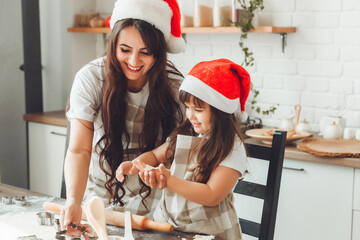 Wall Mural - happy cheerful mother and child in Santa Claus hats are cooking Christmas cookies in the kitchen. new year and Christmas