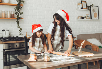 Wall Mural - happy cheerful mother and child in Santa Claus hats are cooking Christmas cookies in the kitchen. new year and Christmas