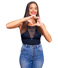 Wall Mural - Young hispanic woman wearing casual clothes smiling in love doing heart symbol shape with hands. romantic concept.