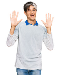 Sticker - Young hispanic man wearing casual clothes showing and pointing up with fingers number ten while smiling confident and happy.