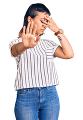 Sticker - Young woman wearing casual clothes covering eyes with hands and doing stop gesture with sad and fear expression. embarrassed and negative concept.