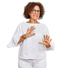 Canvas Print - Beautiful middle age mature woman wearing casual clothes and glasses disgusted expression, displeased and fearful doing disgust face because aversion reaction. with hands raised