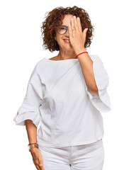 Canvas Print - Beautiful middle age mature woman wearing casual clothes and glasses covering one eye with hand, confident smile on face and surprise emotion.