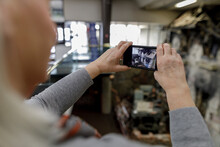 Senior Woman With Smart Phone Photographing Exhibit In War Museum