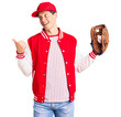 © Krakenimages.com - Young handsome man wearing baseball uniform holding golve and ball pointing thumb up to the side smiling happy with open mouth