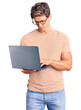 © Krakenimages.com - Young handsome man wearing glasses holding laptop thinking attitude and sober expression looking self confident