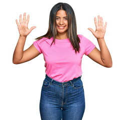 Wall Mural - Young latin girl wearing casual clothes showing and pointing up with fingers number ten while smiling confident and happy.