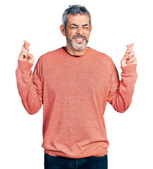 Sticker - Middle age hispanic with grey hair wearing casual sweater gesturing finger crossed smiling with hope and eyes closed. luck and superstitious concept.