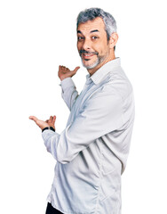 Wall Mural - Middle age hispanic with grey hair wearing casual white shirt inviting to enter smiling natural with open hand