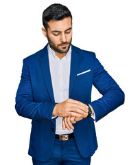 Poster - Young hispanic man wearing business jacket checking the time on wrist watch, relaxed and confident