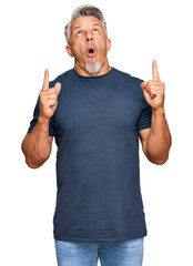 Canvas Print - Middle age grey-haired man wearing casual clothes amazed and surprised looking up and pointing with fingers and raised arms.