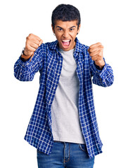 Canvas Print - Young african amercian man wearing casual clothes angry and mad raising fists frustrated and furious while shouting with anger. rage and aggressive concept.