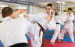 © JackF - Portrait of concentrated young girl wearing white kimono sparring with male opponent during martial arts training in gym, practicing kicking