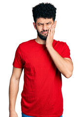 Wall Mural - Young arab man with beard wearing casual red t shirt touching mouth with hand with painful expression because of toothache or dental illness on teeth. dentist