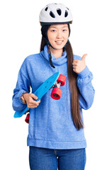 Sticker - Young beautiful chinese woman wearing security helmet holding skate smiling happy and positive, thumb up doing excellent and approval sign