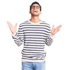 Canvas Print - Hispanic handsome young man wearing casual clothes and glasses crazy and mad shouting and yelling with aggressive expression and arms raised. frustration concept.