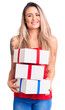 © Krakenimages.com - Young beautiful blonde woman holding birthday gifts looking positive and happy standing and smiling with a confident smile showing teeth