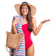 © Krakenimages.com - Young beautiful latin girl wearing swimwear and summer hat holding beach towel and bag celebrating victory with happy smile and winner expression with raised hands