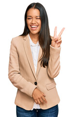 Poster - Beautiful hispanic woman wearing business jacket smiling with happy face winking at the camera doing victory sign. number two.