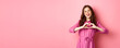 © Mix and Match Studio - Beautiful romantic girl smiling, showing heart gesture, standing in lovely dress against pink background