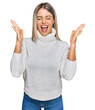 © Krakenimages.com - Beautiful blonde woman wearing casual turtleneck sweater celebrating mad and crazy for success with arms raised and closed eyes screaming excited. winner concept