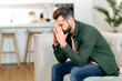 © Kateryna - Unhappy frustrated caucasian man, sit on sofa in living room with his head down and his eyes closed, experiencing personal problems, migraine, stress, loneliness, needs psychological support and rest