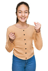 Beautiful brunette little girl wearing casual sweater excited for success with arms raised and eyes closed celebrating victory smiling. winner concept.