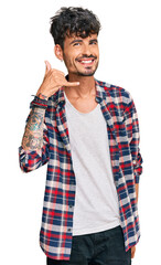 Sticker - Young hispanic man wearing casual clothes smiling doing phone gesture with hand and fingers like talking on the telephone. communicating concepts.