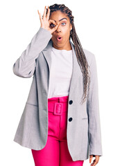 Sticker - Young african american woman with braids wearing business clothes doing ok gesture shocked with surprised face, eye looking through fingers. unbelieving expression.