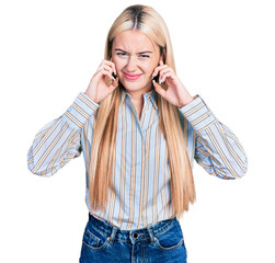 Wall Mural - Beautiful blonde woman wearing casual striped shirt covering ears with fingers with annoyed expression for the noise of loud music. deaf concept.