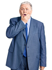 Wall Mural - Senior grey-haired man wearing business jacket looking fascinated with disbelief, surprise and amazed expression with hands on chin