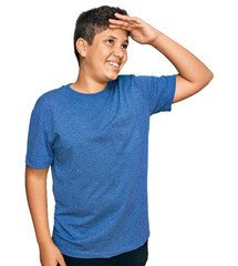 Poster - Teenager hispanic boy wearing casual clothes very happy and smiling looking far away with hand over head. searching concept.