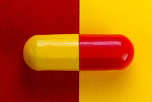 Close Up The Red Yellow Capsules Lined Up On A Yellow And Red Background. With An Eye Level Camera Angle. Minimalist Concept, Health, Drugs, Addictive, Therapeutic