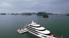 aerial flying over white luxury mega yacht in Ha Long Bay Vietnam on cloudy day