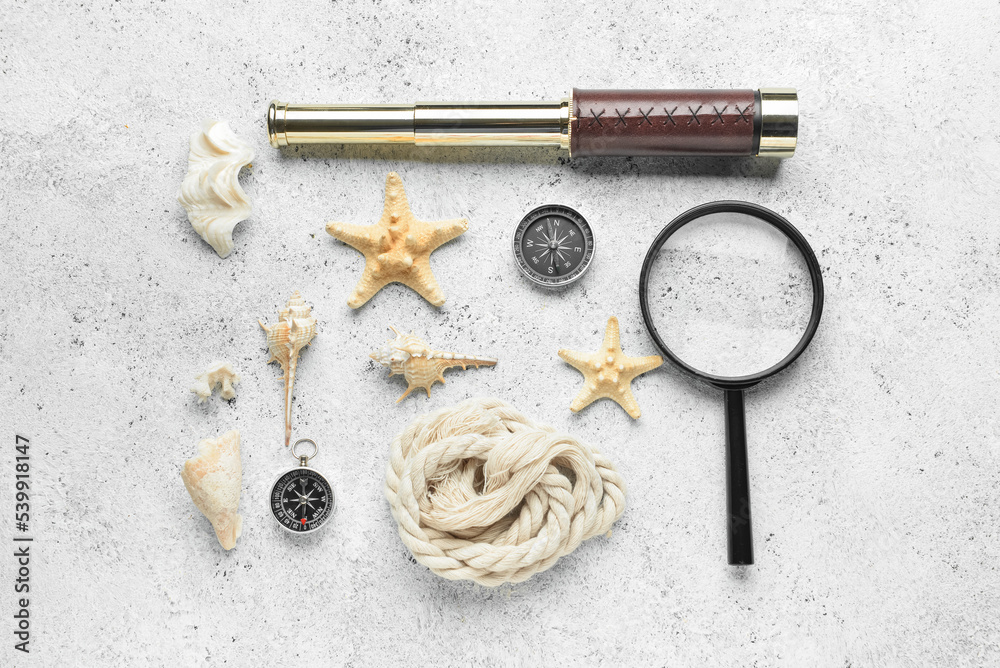 Vintage spyglass, magnifier, compasses, rope and seashells on light background