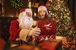 © ZaStock - Santa Claus surprising little girl while open magical gift box near Christmas tree. New Year concept