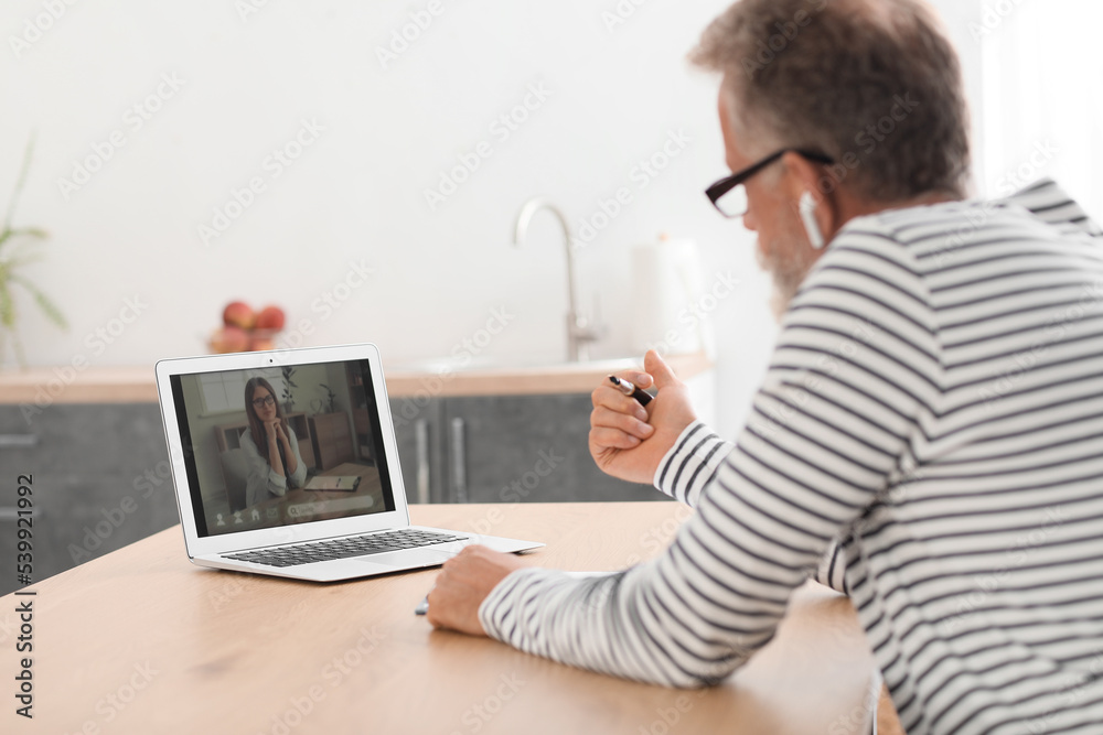 Male psychologist video chatting with patient in kitchen