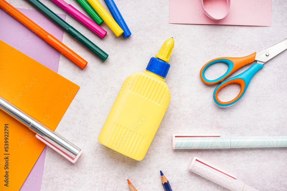 Bottle of glue and stationery on light background