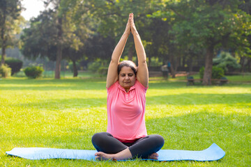 indian woman doing breathing yoga exercise in the park, Asian female meditation pose, healthcare.