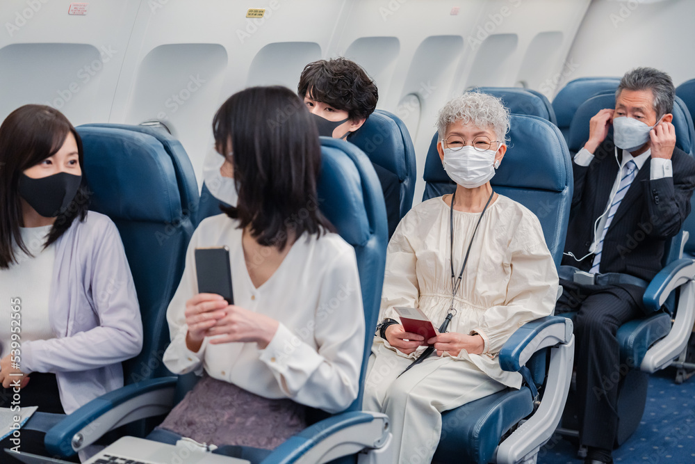 Foto de Stock マスクをして飛行機に乗る乗客 | Adobe Stock