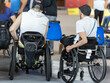 © GioRez - View from Behind of Two Boys Sitting in their Wheelchairs Watching other People