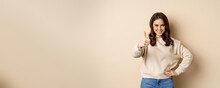 Beautiful Young Woman, Student Showing Thumbs Up In Approval, Recommending Store, Standing Over Beige Background