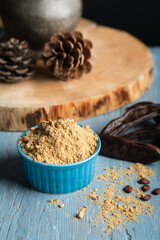 Wall Mural - Carob pods and carob powder over a blue wooden background.