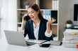 © Kritdanai - Asian businesswoman talking on phone, using laptop, looking at screen, entrepreneur manager consulting client by call, looking at computer screen, discussing project, reading information