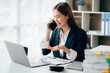 © Kritdanai - Happy young asian businesswoman sitting on her workplace in the office. Young woman working at laptop in the office