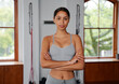 Portrait of focused young biracial woman looking at camera with arms crossed at the gym