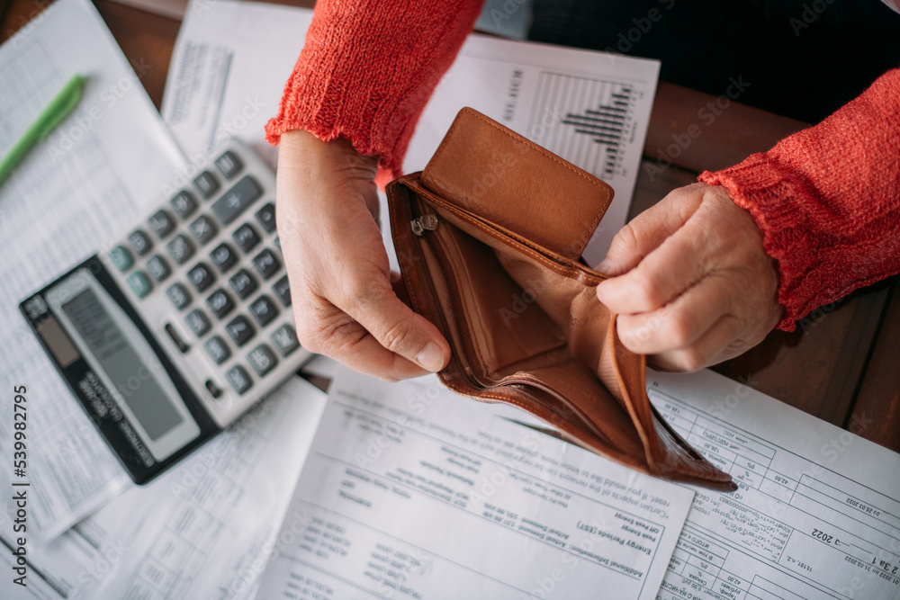 The hands of an elderly woman with an empty wallet and a lot of utility ...