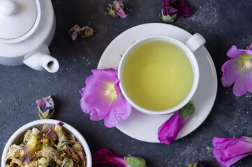 Wall Mural - Cup of hollyhock tea with dried and fresh hollyhock blossom on rustic table