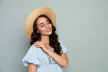 Canvas Print - Beautiful young woman with straw hat on light grey background. Space for text